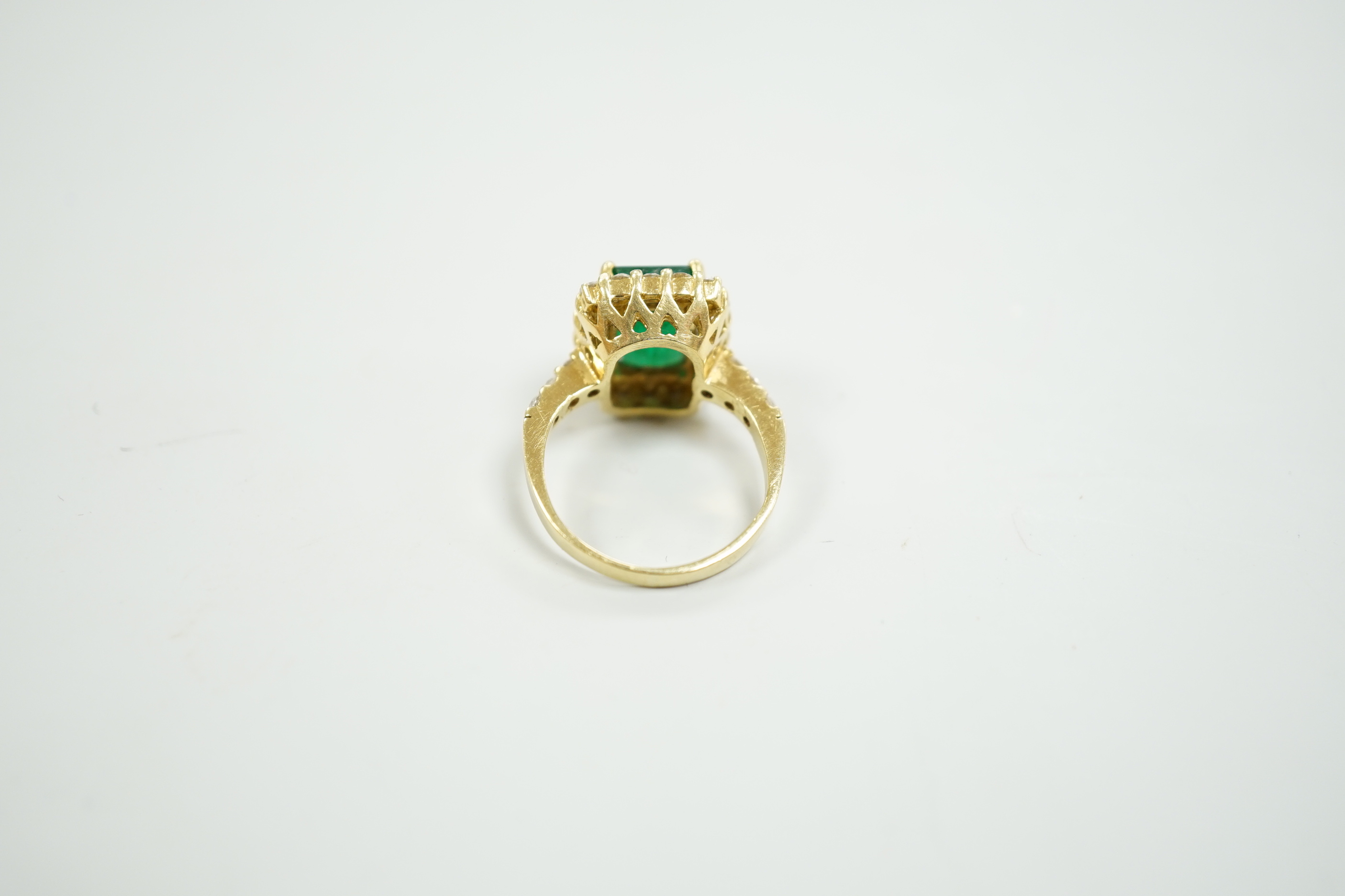 A modern 18ct gold and single stone emerald set dress ring, with diamond set border and shoulders, size L, gross weight 6.5 grams, with accompanying Beverley Hills Gemological Laboratory appraisal certificate date 18/11.